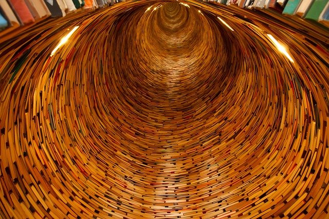 A tunnel is created out of books. It looks like the books were sliced in the process.