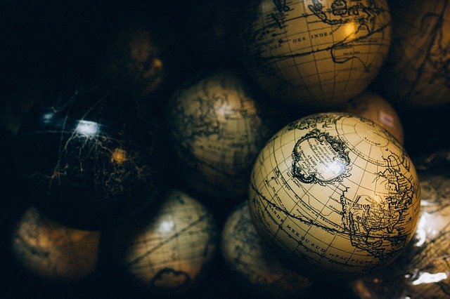 Mini balls with globe maps on them stack up. Some are black and some are yellow.